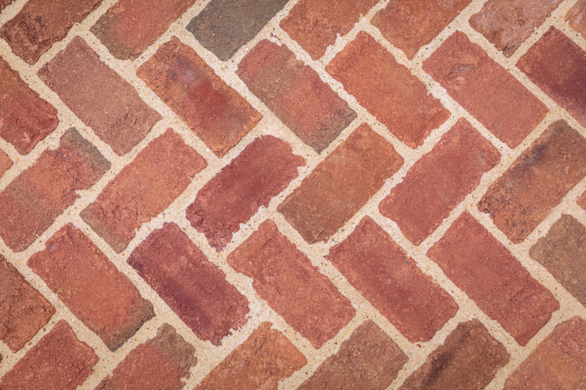 Close-up of a crisscross brick pattern, featuring reddish-brown bricks with light gray mortar, creating a textured and rustic appearance.