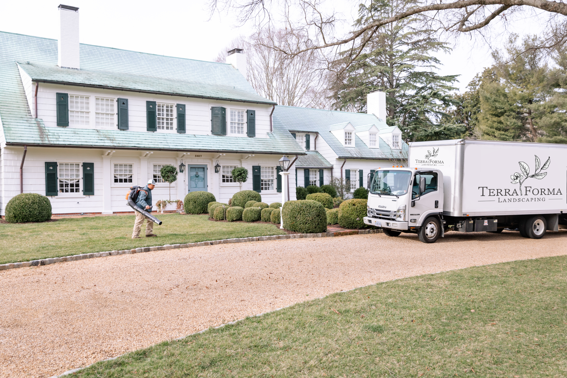 Landscaping crew using blower to clean driveway at a large estate home