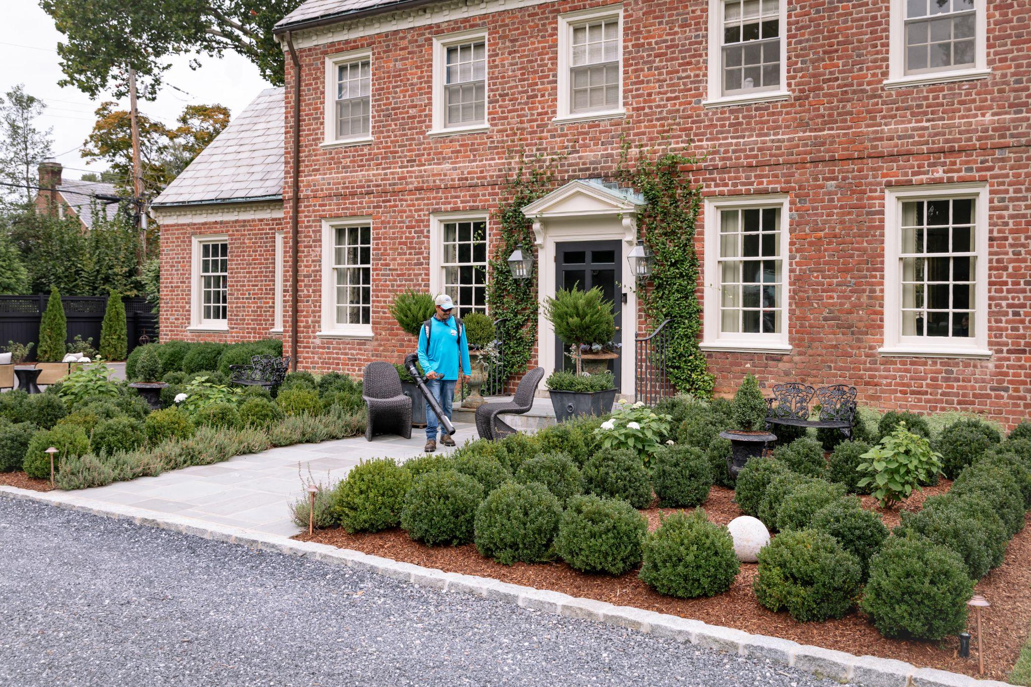 Worker using a leaf blower on a manicured garden path.
